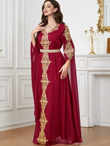 Detail der goldenen Bestickung und Perlenverzierung am burgunderroten Maxikleid