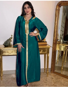 Detail of dark green velvet kaftan dress with intricate gold embroidery on cuffs