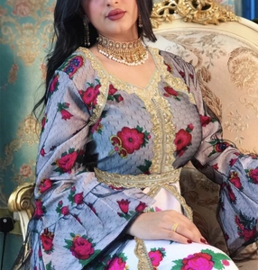 Detailed view of ethnic kaftan dress with red floral prints and gold lace embroidery