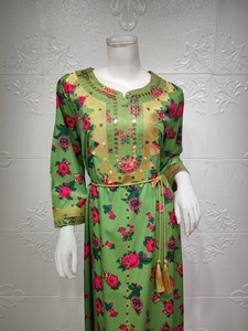 Macro shot of gold woven waist rope and embroidery details on a green floral dress