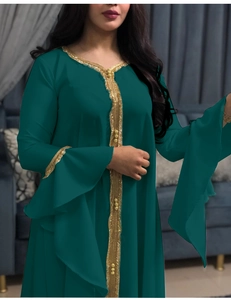 Close-up of golden wavy embroidery and layered ruffle cuffs on a dark green dress