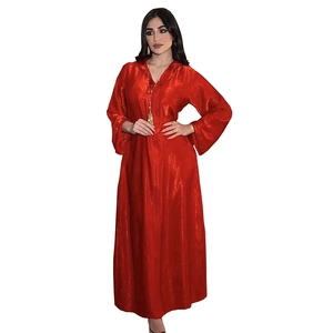 Detail of red velvet hooded kaftan dress with luxury tassel pendant and shimmering finish