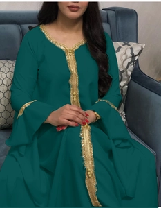 Detail of green kaftan with gold lace embroidery and flare sleeves on velvet sofa