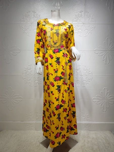 Close-up of golden embroidery and tassel belt on a yellow floral kaftan dress