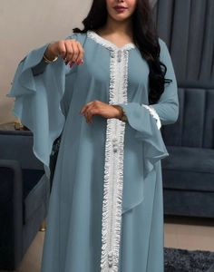 Detail of grey blue kaftan featuring white lace embroidery and tiered ruffle sleeves