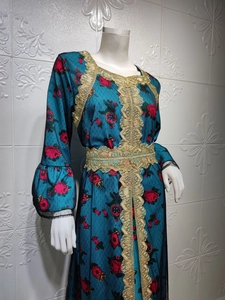 Detail of dark teal kaftan featuring red rose print and golden lace embroidery on the front
