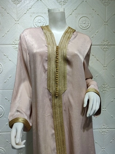 Detail of champagne satin hooded dress featuring gold embroidery and spherical buttons