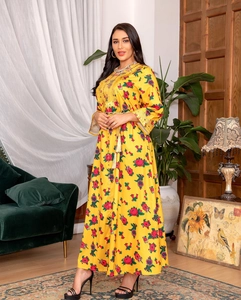 Detail of yellow floral dress with gold tassel belt and elegant embroidery at cuffs