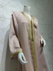 Detailed view of champagne satin kaftan with intricate gold embroidery and buttons
