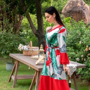 Détail de robe imprimé palmier tropical avec ourlet à volants rouges et ceinture assortie