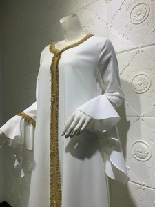 Detail of white abaya with gold braided tassel edges and layered lotus sleeves