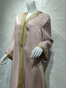 Detail of gold embroidery and textured satin fabric on a champagne kaftan dress