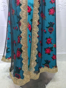 Detailed view of floral embroidery and gold lace trim on the peacock blue mesh dress