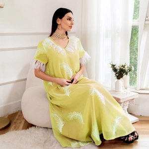 Detail of light green maxi dress featuring white feather trim on the V-neck and sleeves
