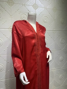 Detail of red satin kaftan with intricate embroidery and traditional knot buttons