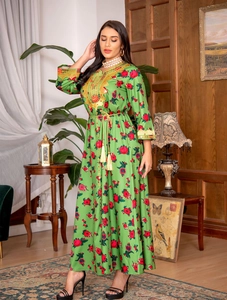 Detail of green long-sleeved ethnic dress featuring golden embroidery and floral prints