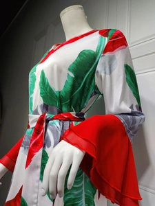 Détail d'une robe blanche à manches longues avec feuilles de palmier et motifs floraux