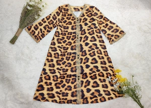 Detailed view of leopard print dress featuring golden lace trim and black decorative buttons