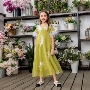 Detail of lime green girls dress featuring white feather trim and embroidery
