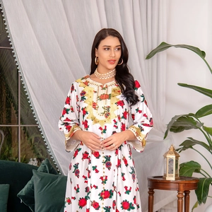 Close-up of golden embroidery and floral patterns on a white bohemian maxi dress