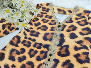 Detail of leopard print dress featuring golden lace trim and decorative beads on neckline