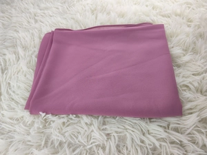 Close-up of layered chiffon hijab in soft lotus pink on a white plush surface