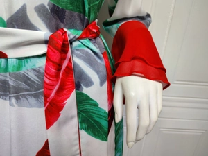 Détail des poignets à volants rouges et de l'imprimé de feuilles tropicales sur la robe