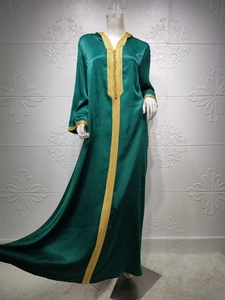 Detail view of dark green kaftan dress with golden embroidery and braided trim accents