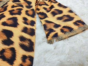 Detailed view of leopard print fabric with delicate gold lace trim on the garment sleeve