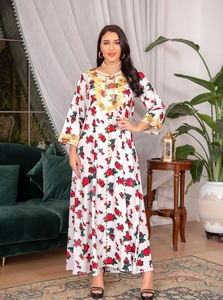 Detailed embroidery on white long-sleeve floral maxi dress in a cozy indoor setting