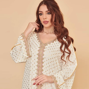 Detail eines weißen Kaftan-Kleids mit goldenen Rautenprints und Perlenstickerei