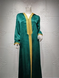 Detailed embroidery on a dark green velvet Moroccan kaftan dress with gold lace trim