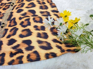 Detail of leopard print fabric with golden lace trim and decorative buttons for dresses