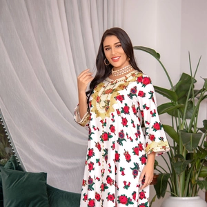 Close-up of golden embroidery details and red floral patterns on a white ethnic dress