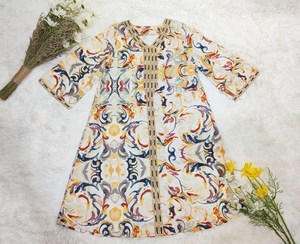 Détail de la broderie dorée et de l'imprimé floral baroque sur l'abaya blanche