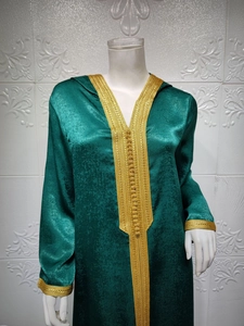 Detail of golden geometric embroidery on the collar and cuffs of a green satin kaftan