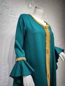 Detail of dark green dress with gold embroidered trim and lotus leaf ruffle sleeves