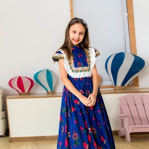Detail of royal blue floral dress with white lace and colorful pom-poms on the sleeves