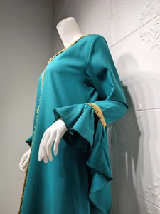 Detail of teal abaya featuring intricate gold lace embroidery and layered ruffle sleeves
