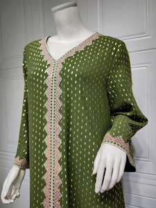 Detailaufnahme von grünem Kaftan-Kleid mit Goldfoliendruck und Häkelspitze am Ausschnitt