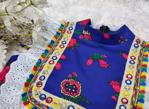 Detail of ethnic floral embroidery and colorful tassel trim with mirror sequins on navy top