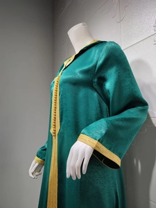 Detailed view of dark green velvet kaftan with golden braided lace and decorative buttons