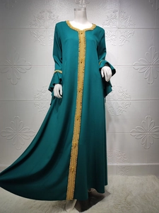 Detail of dark green dress with gold embroidery and ruffled sleeves on mannequin