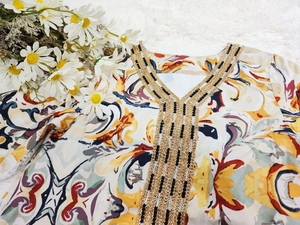 Détail du col en V avec broderies dorées et paillettes sur abaya imprimée