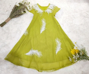 Close-up of green mesh dress featuring delicate white feather embroidery and V-neck detail