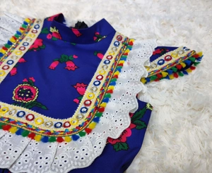 Detail of embroidered floral patterns, sequins, and colorful tassels on kids summer dress