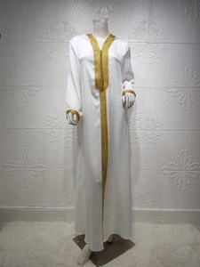 Close-up of golden embroidery and sphere buttons on white hooded abaya neckline