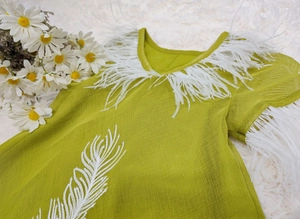 Detail of lime green dress featuring soft white ostrich feathers and embroidery detail
