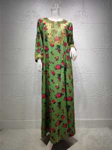 Close-up of green floral dress with intricate gold embroidery and sequin sleeve detail