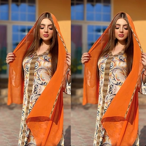 Détail de l'abaya imprimée avec motifs cachemire et foulard orange sous une lumière chaude